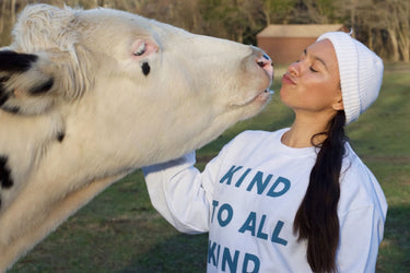 Axiology founder Ericka kissing a cow in Kind to All Kind sweatshirt